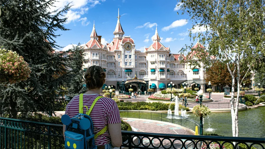 Kvinna med en mussepiggryggsäck som tittar på Disneyland park.