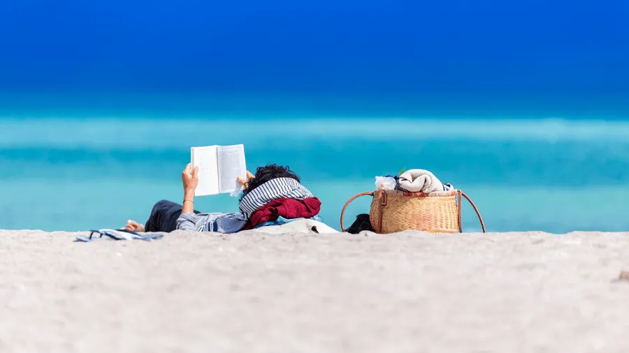 Person som läser en bok på stranden.