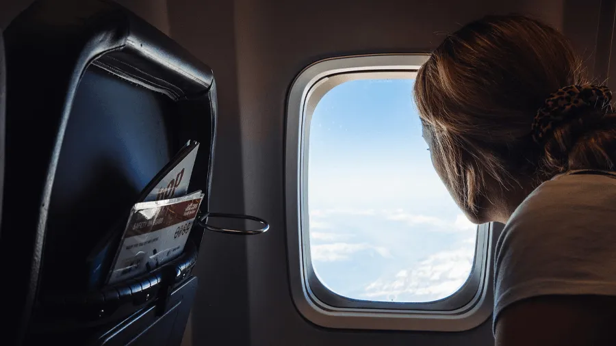 Resenär som tittar ut genom flygplansfönstret.