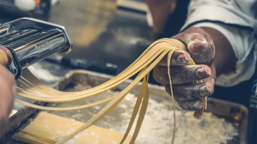 En person som gör pasta på en matresa i Italien.