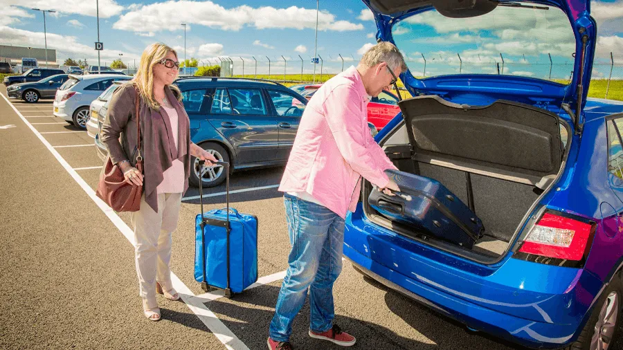Ett par på en flygplats som ska packa ur sin bil.