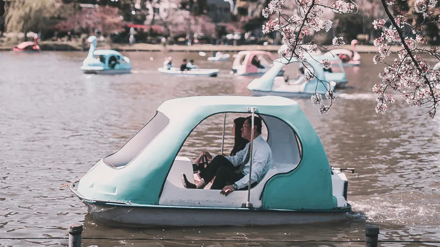 Folk som åker i båtar i Ueno park.