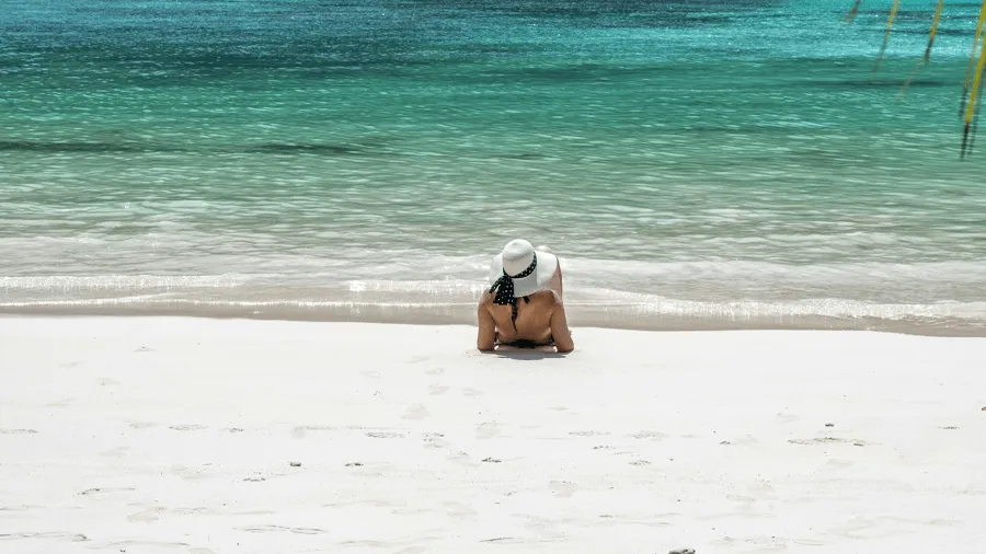 En kvinna på en vit sandstrand i Seychellerna.