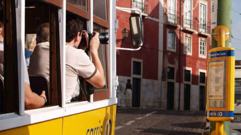 En man på Tram 28 som fotograferar Lissabon.