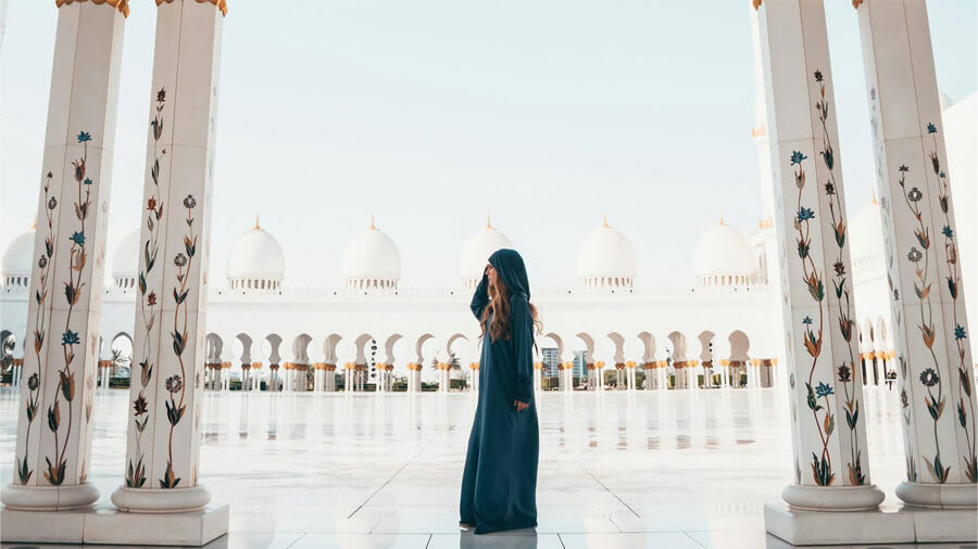 En kvinna vid en moské på sin Abu Dhabi resa.