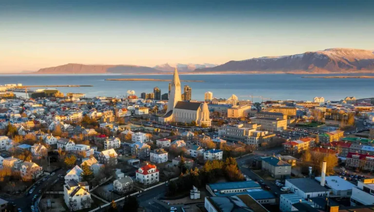 Utsikt över Reykjavik med Hallgrímskirkja, havet och fjällen i kvällsljus.