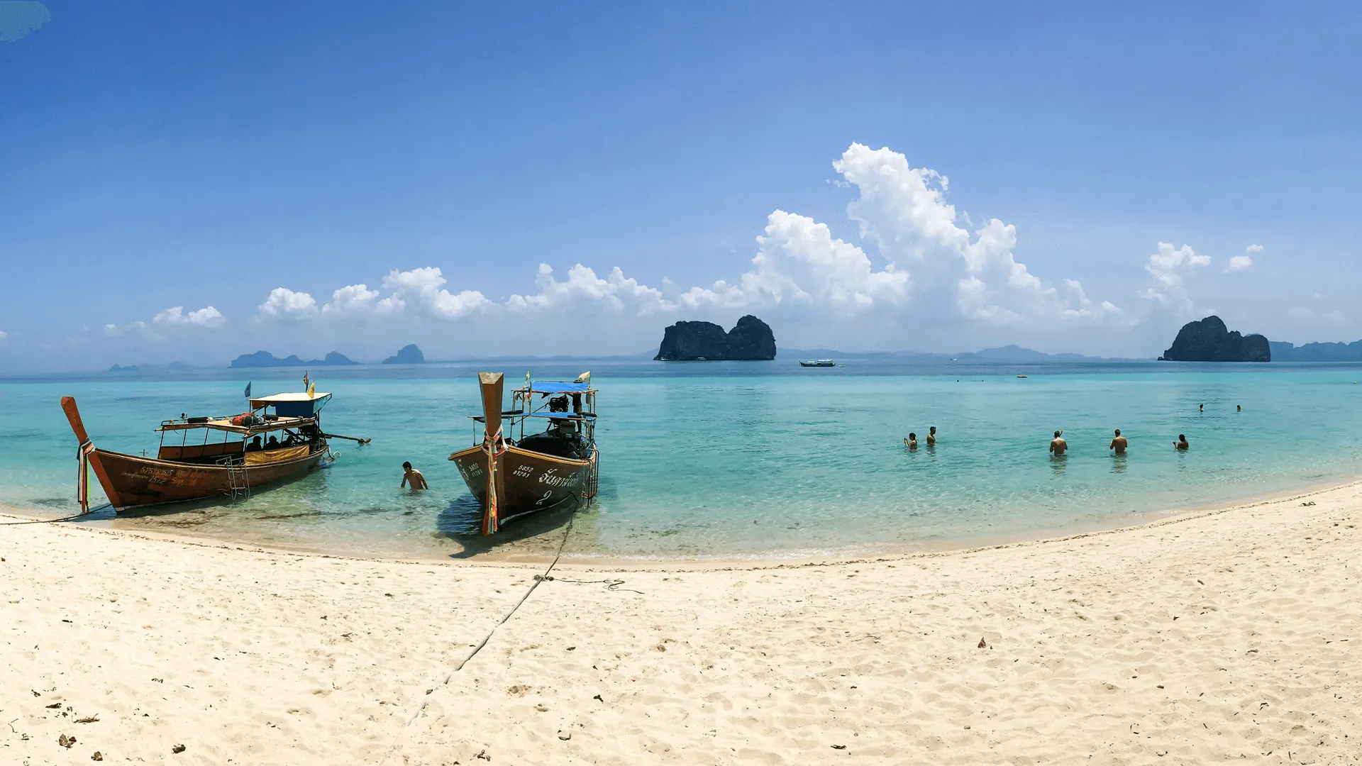 Thailändska båtar vid sandstranden i Koh Lanta.
