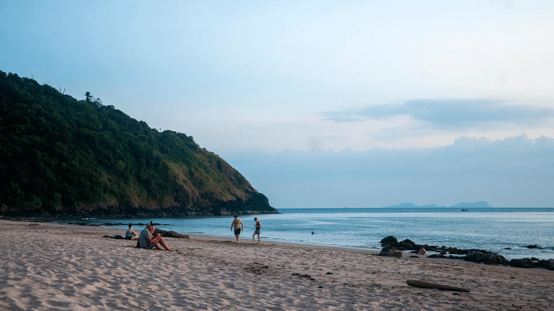 Folk som sitter på stranden under kvällen i Koh Lanta.