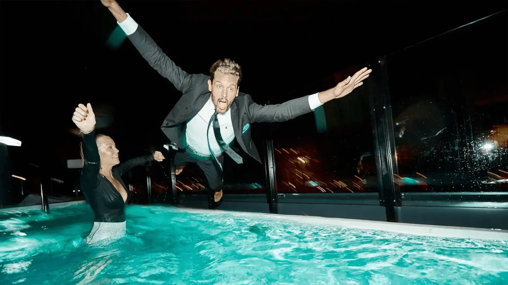 Finklädda personer som hoppar i poolen.