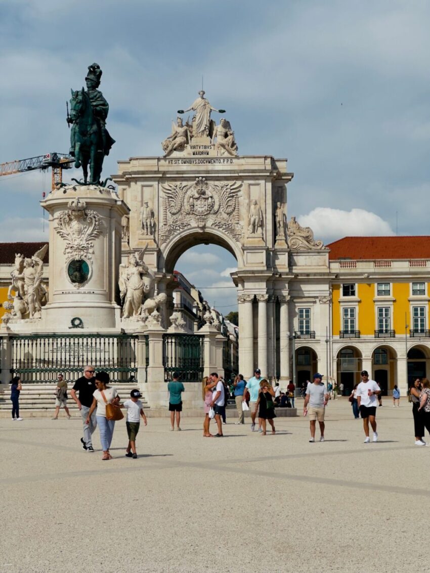 Resenärer vid torget Praça do Comércio med den ikoniska triumfbogen