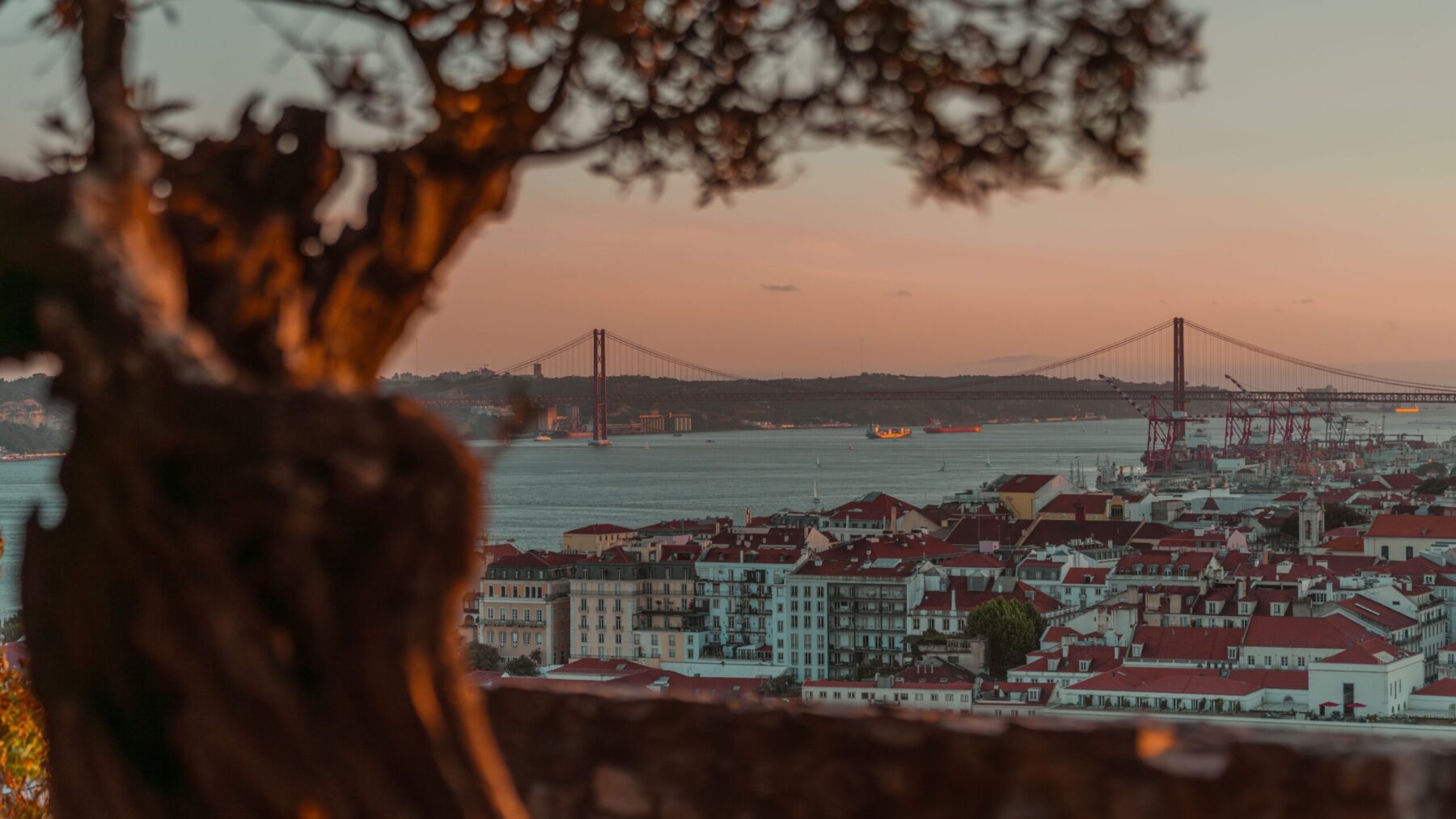 Solnedgång vid bron 25 de Abril över floden Tejo