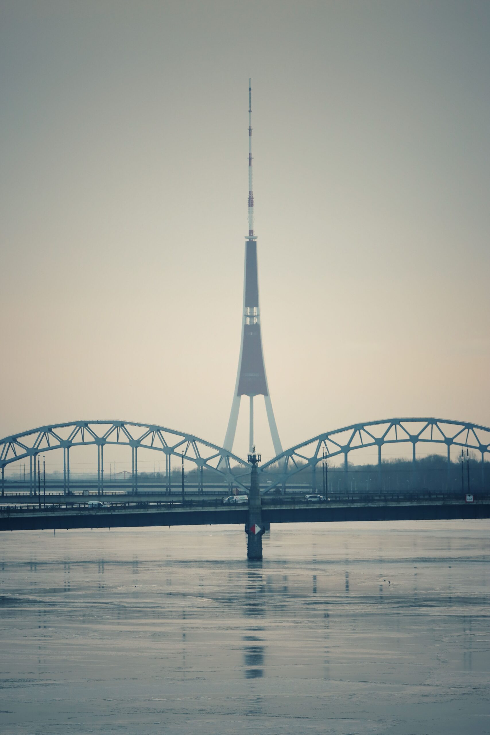 Järnvägsbro över floden Daugava med TV-tornet i bakgrunden, Riga