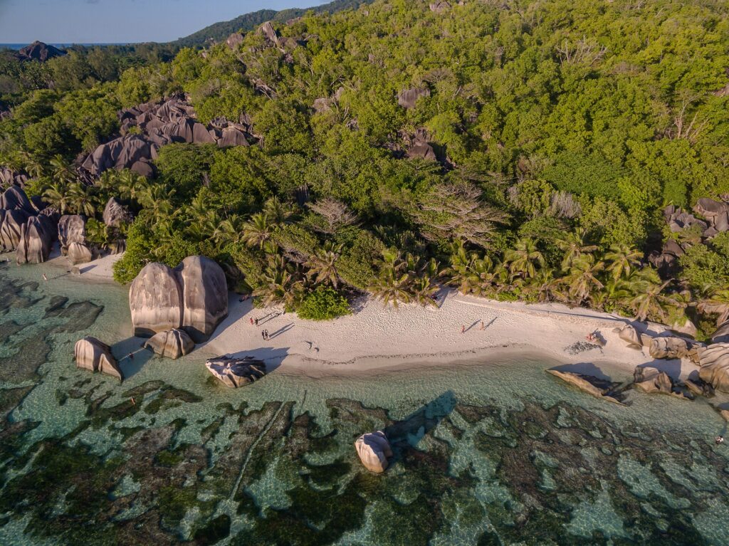 Flygbild över stranden Anse Source d’Argent med granitklippor och palmer på La Digue, Seychellerna