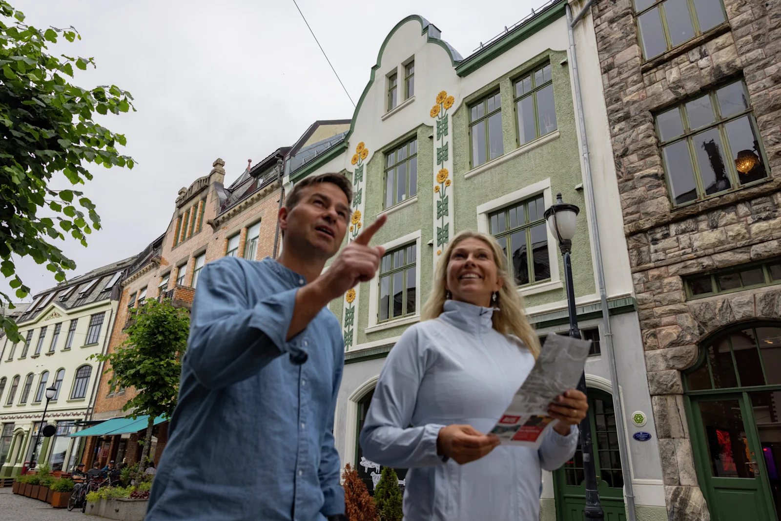Två resenärer med karta framför jugendfasader i Ålesund