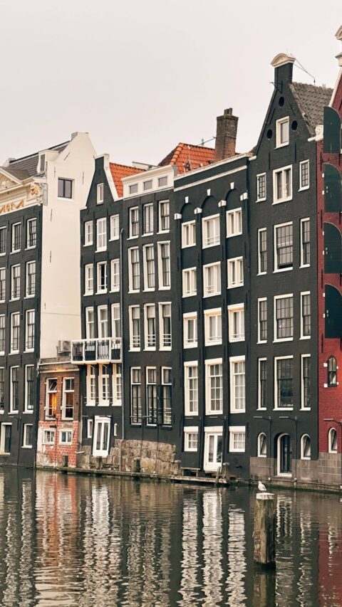 Historiska kanalhus med trappgavlar speglar sig i en kanal i Amsterdam