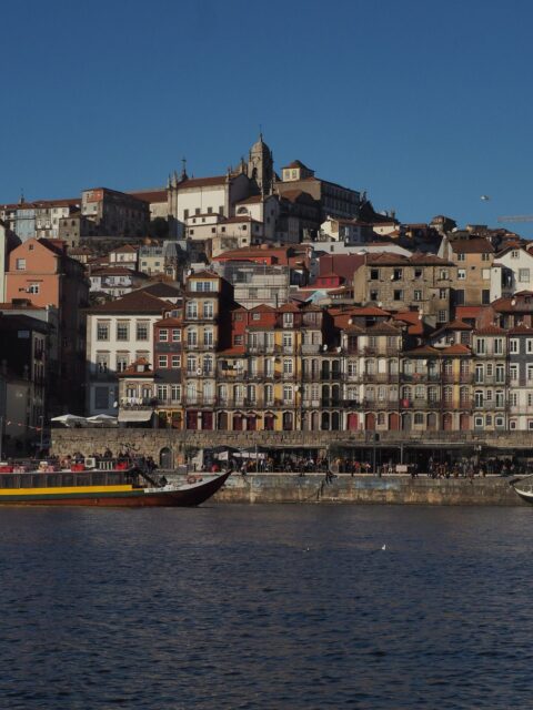 Färgglada hus i Ribeira vid floden Douro i Porto med en rabelobåt i förgrunden