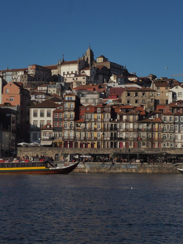 Färgglada hus i Ribeira vid floden Douro i Porto med en rabelobåt i förgrunden