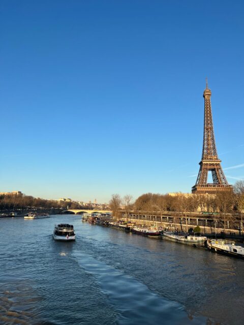 Eiffeltornet vid Seine i Paris med en turistbåt på floden