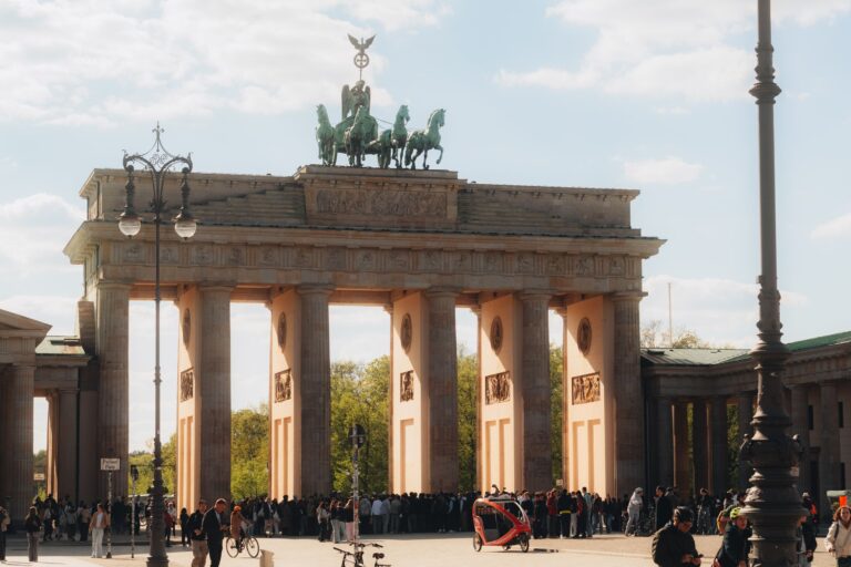 Brandenburger Tor i Berlin en solig dag med turister och cyklister framför porten