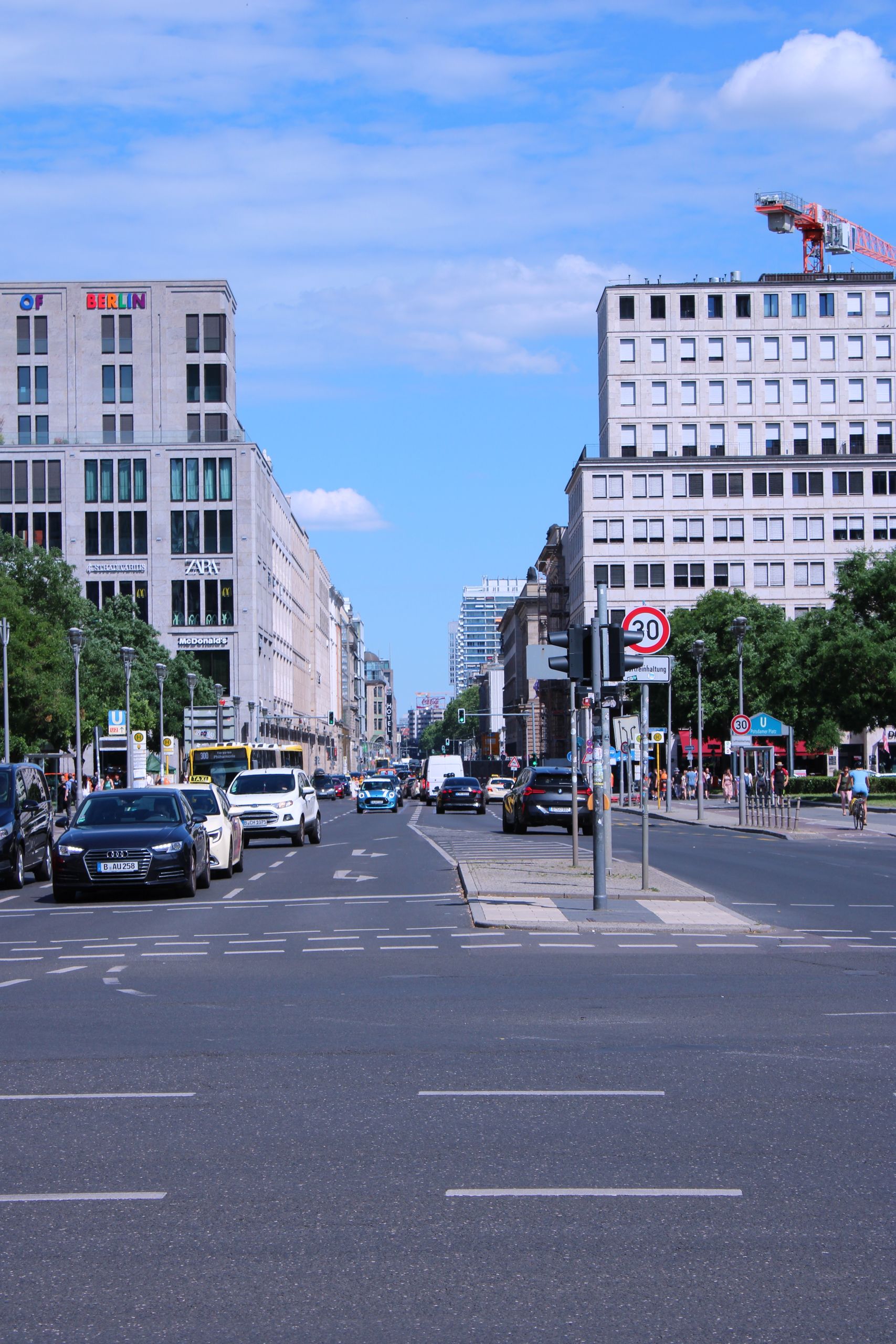 Kurfürstendamm i Charlottenburg, Berlin, med trafik och klassiska fasader under blå himmel