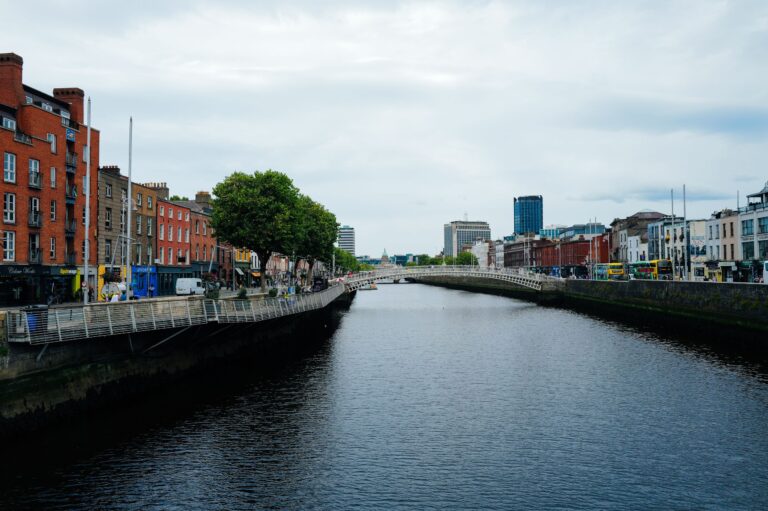 Ha’penny Bridge över floden Liffey i Dublin med stadens hus längs kajen