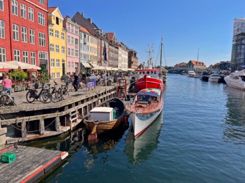 Nyhavn i Köpenhamn med färgglada hus, båtar och cyklar längs kajen en solig dag