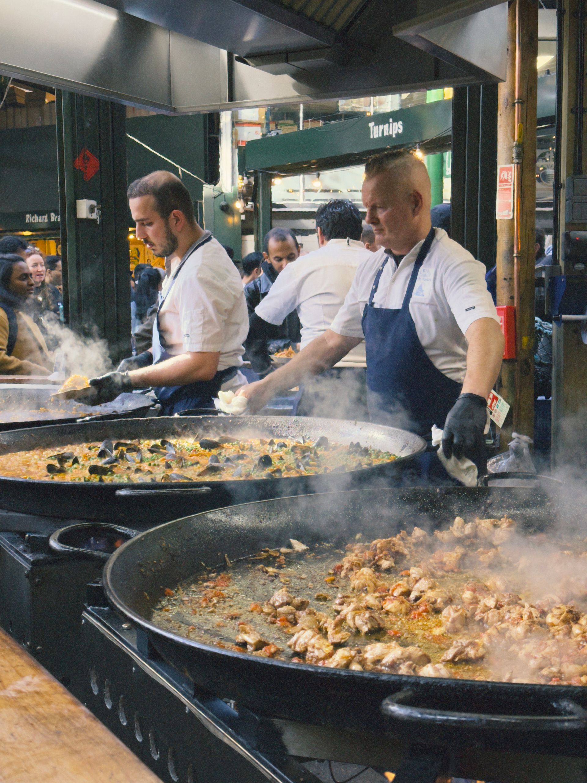 Kockar lagar mat i stora pannor på Borough Market i London