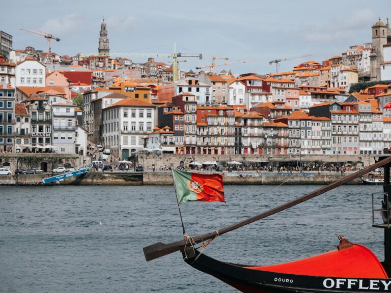Ribeira i Porto med färgglada hus vid Douro och en traditionell rabelobåt på floden