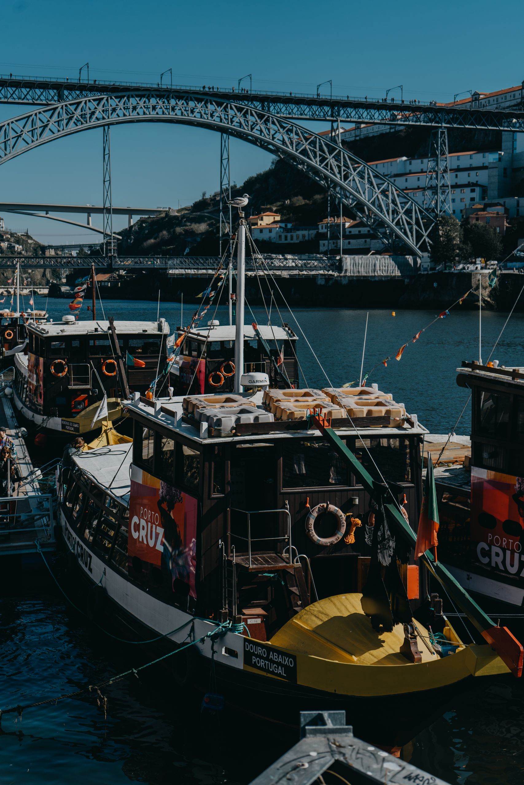 Båtar vid kajen i Porto med Dom Luís I-bron i bakgrunden