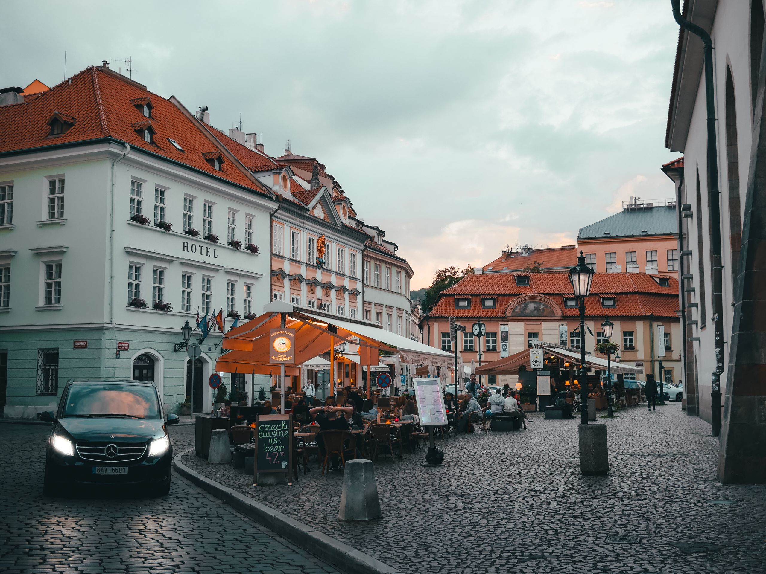 Uteservering på en kullerstensgata i Gamla stan i Prag på kvällen