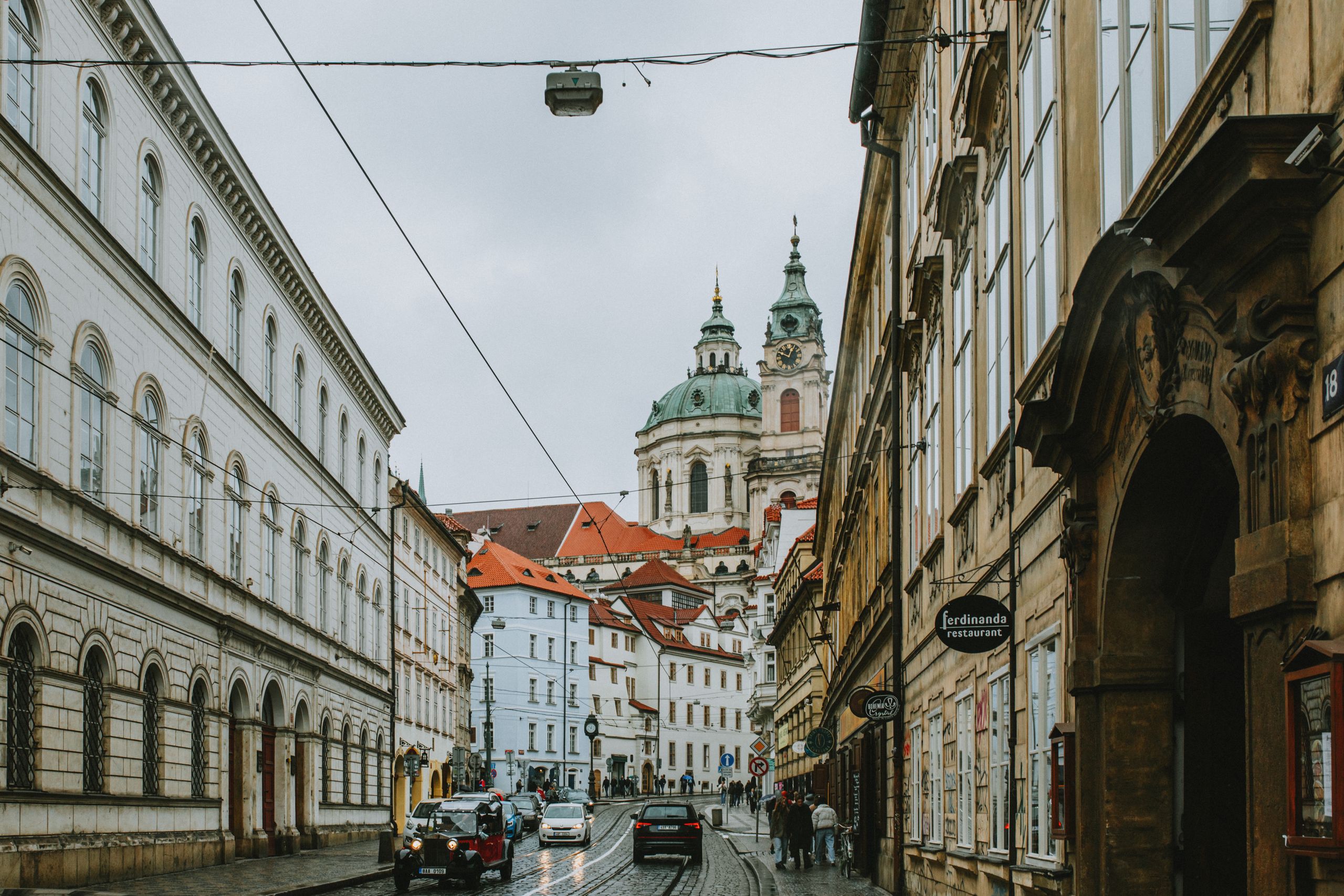 Gata i Malá Strana i Prag med Nikolaikyrkans kupol och torn i fonden